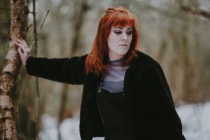 a woman leaning her hand against a tree and looking away with a disappointed look on her face.