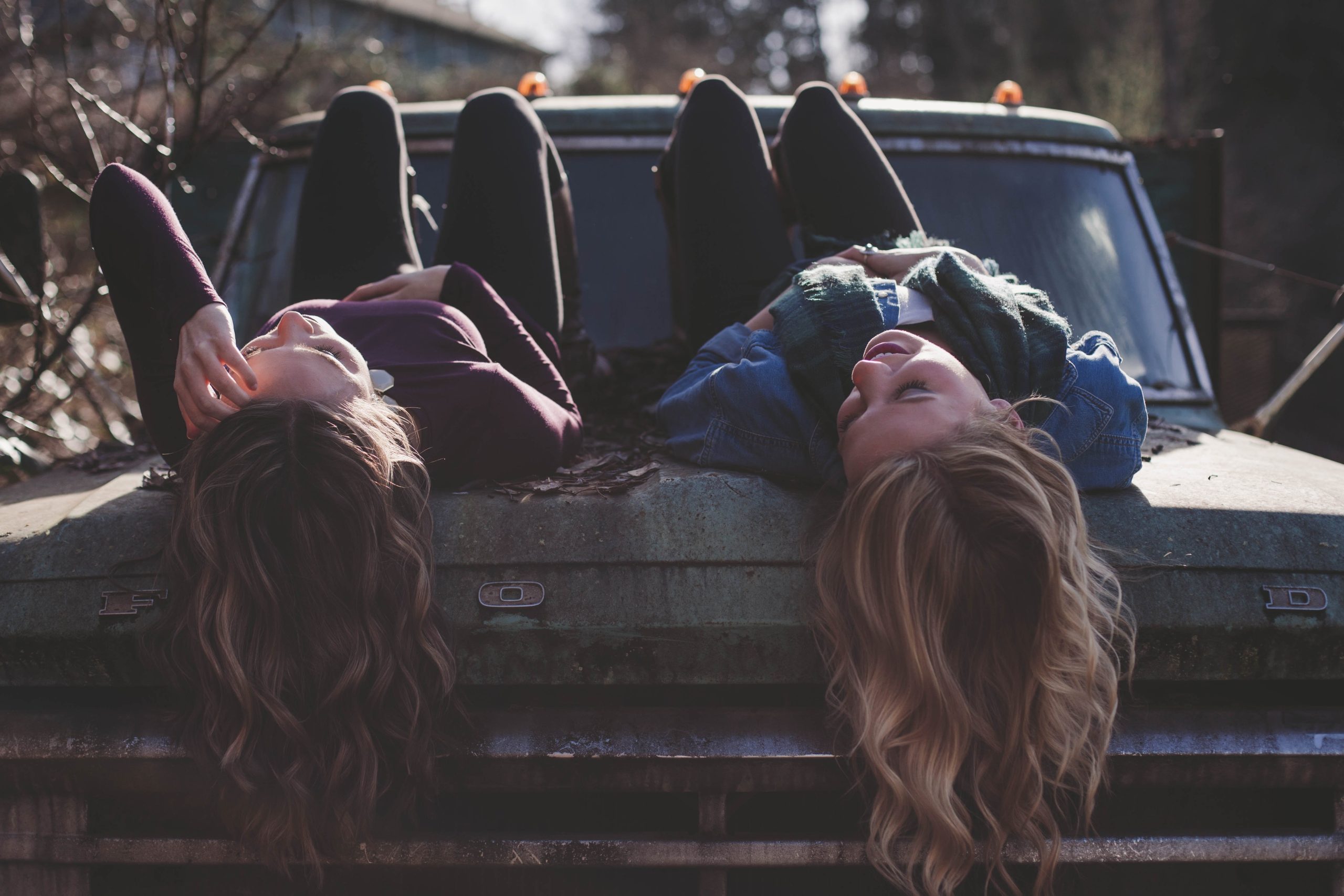 two young women lying down, their blond and brunette hair cascading down stone steps.